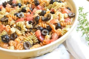 yellow bowl with pasta salad on towel and oregano