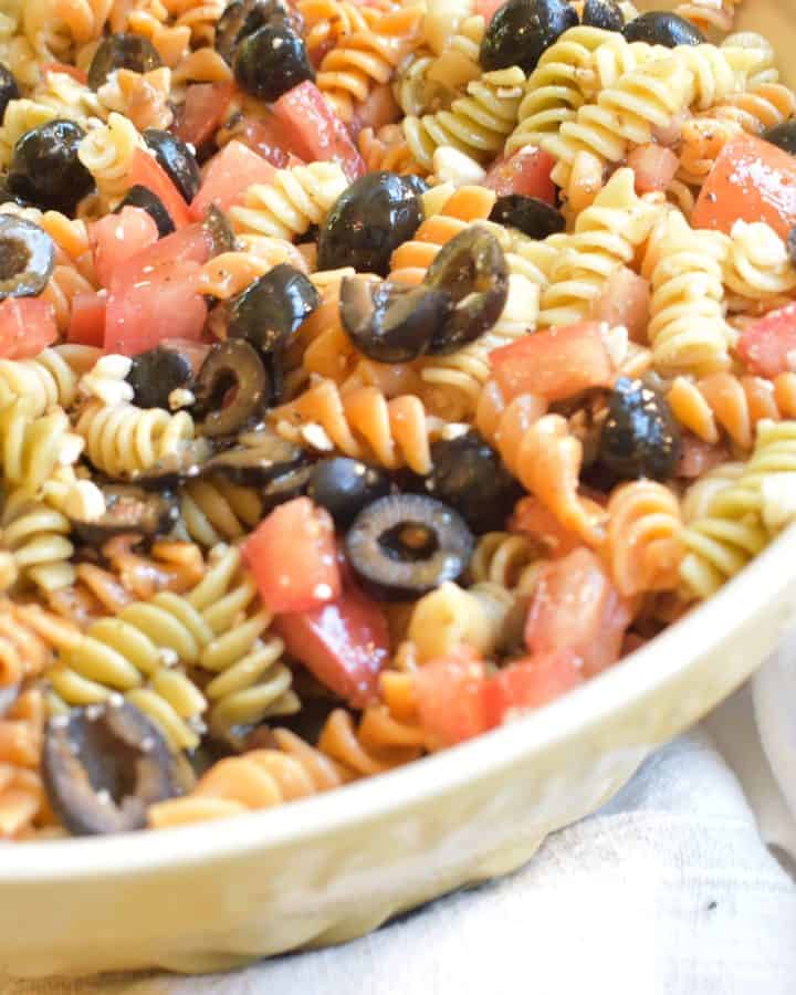 yellow bowl with pasta salad on towel and oregano